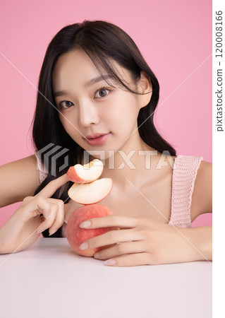 A woman in her 20s posing with a peach on the table 120008166