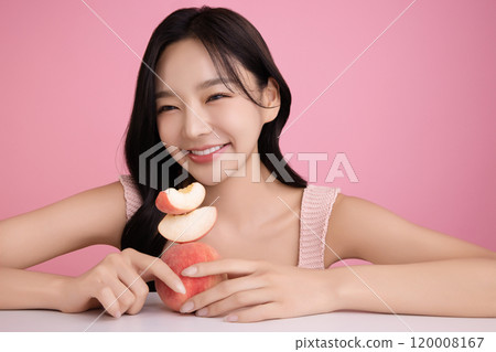 A woman in her 20s posing with a peach on the table 120008167