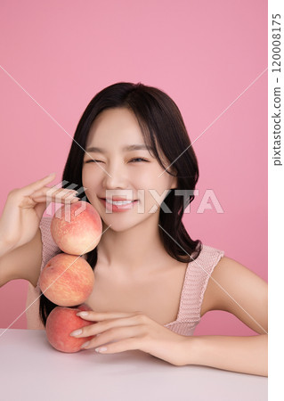 A woman in her 20s posing with a peach on the table 120008175
