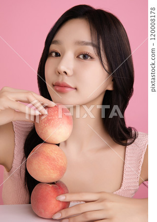 A woman in her 20s posing with a peach on the table 120008178