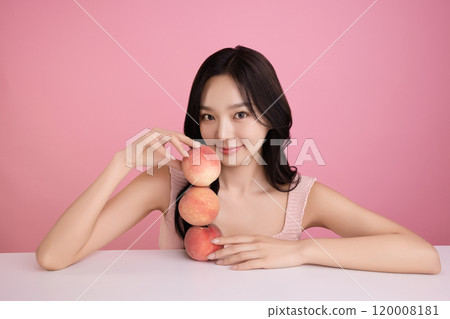 A woman in her 20s posing with a peach on the table 120008181