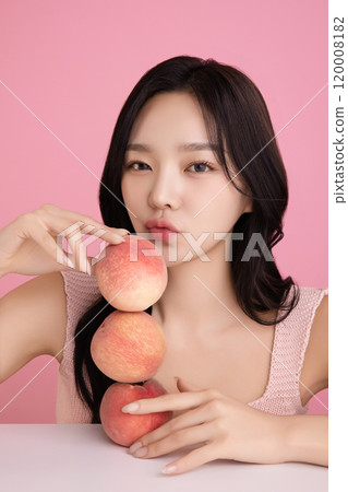 A woman in her 20s posing with a peach on the table 120008182