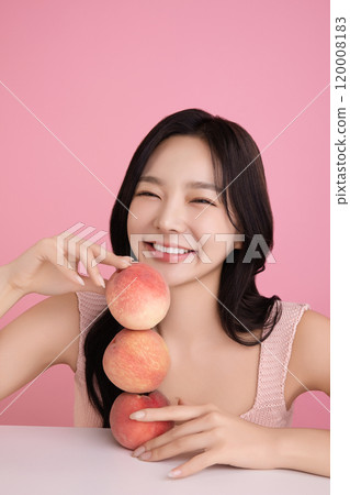A woman in her 20s posing with a peach on the table 120008183