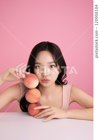 A woman in her 20s posing with a peach on the table 120008184