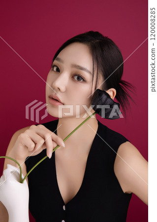 A woman in her 20s posing in front of black poppy flowers 120008285