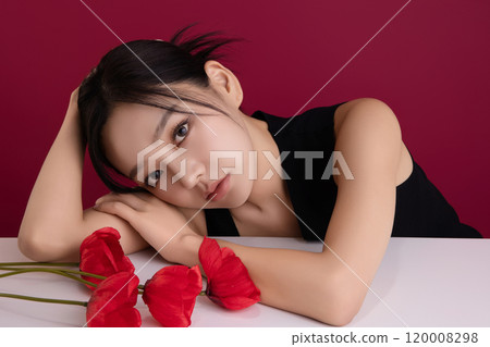 A woman in her 20s posing with a red poppy flower A woman in her 20s posing with a red poppy flower 120008298