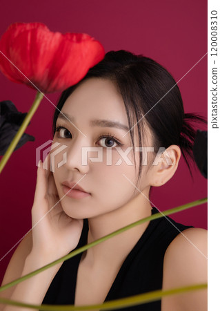 A woman in her 20s showing an elegant pose using poppy flowers 120008310