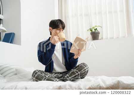 A man in his 20s leisurely reading in bed A man in his 20s leisurely reading in bed 120008322
