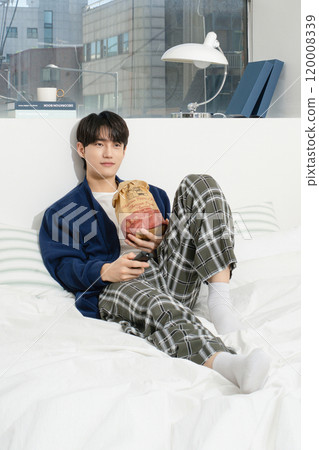 A man in his 20s operating a remote control while lying in bed A man in his 20s operating a remote control while lying in bed 120008339