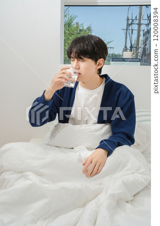 A man in his 20s who stands up briefly and drinks water 120008394