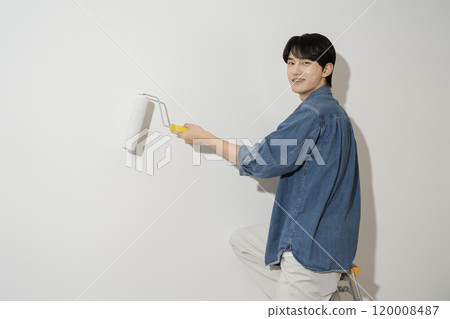 A man in his 20s painting a wall 120008487