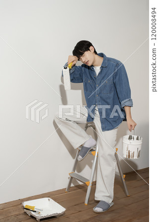 A man in his 20s painting a wall 120008494