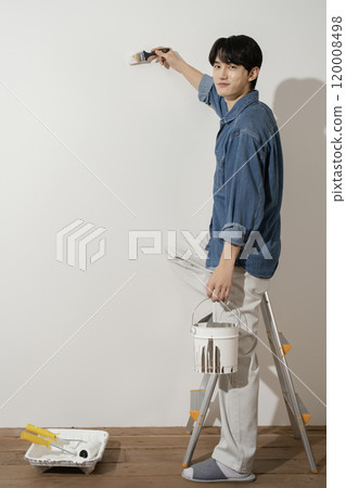 A man in his 20s painting a wall 120008498