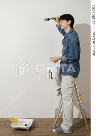 A man in his 20s painting a wall A man in his 20s painting a wall 120008502