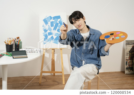 A man in his 20s painting on canvas with paints A man in his 20s painting on canvas with paints 120008534