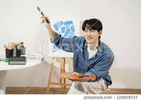 A man in his 20s painting on canvas with paints A man in his 20s painting on canvas with paints 120008537