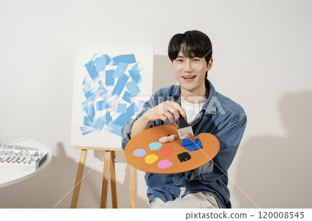 A man in his 20s painting on canvas with paints A man in his 20s painting on canvas with paints 120008545