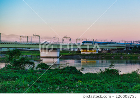 Noborito: Odakyu Line trains shining in the setting sun as seen from the Tama River bank 120008753