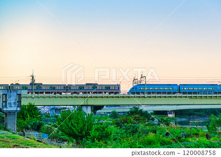 Noborito: Odakyu Line trains shining in the setting sun as seen from the Tama River bank 120008758