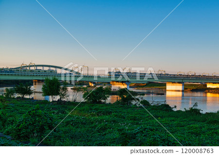 Noborito: Odakyu Line trains shining in the setting sun as seen from the Tama River bank 120008763