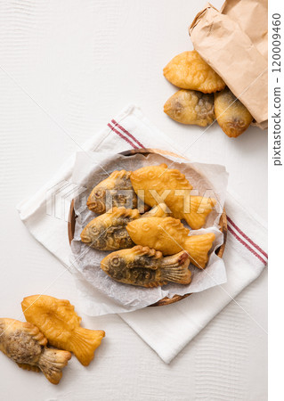 Bungeoppang spilling out of a paper bag and on a plate 120009460