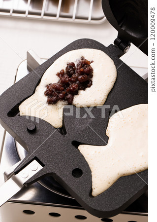 Putting bungeoppang ingredients into a household bungeoppang machine and baking them 120009478