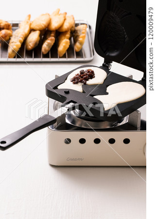 Putting bungeoppang ingredients into a household bungeoppang machine and baking them 120009479