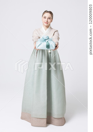 Western woman wearing Hanbok and holding a gift wrapped in Korean style 120009803