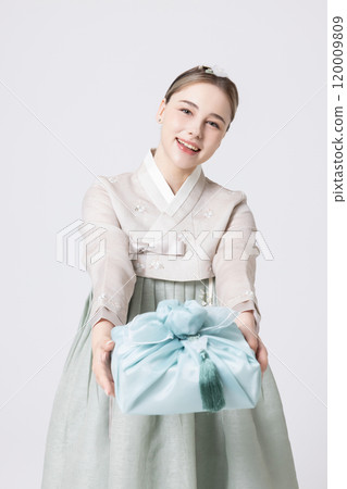 Western woman wearing Hanbok and holding a gift wrapped in Korean style 120009809