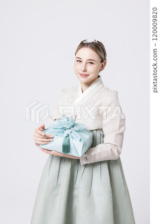 Western woman wearing Hanbok and holding a gift wrapped in Korean style 120009820