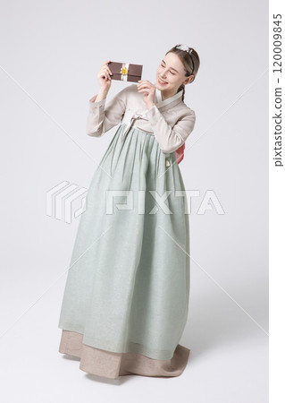 A foreign woman wearing traditional Korean hanbok holding a holiday gift 120009845