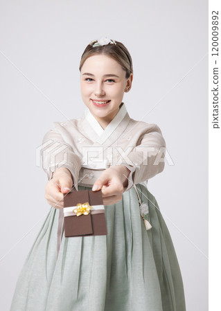 A foreign woman wearing traditional Korean hanbok holding a holiday gift 120009892