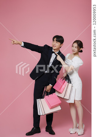 A couple wearing dresses and suits and holding shopping bags A couple wearing dresses and suits and holding shopping bags 120009953