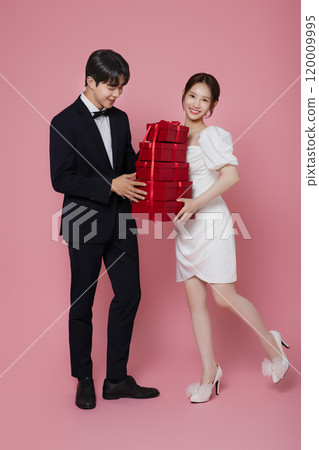A couple wearing dresses and suits and holding shopping bags 120009995
