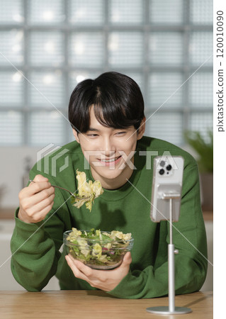 A man in his 20s managing his diet by eating salad 120010090