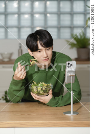 A man in his 20s managing his diet by eating salad 120010091