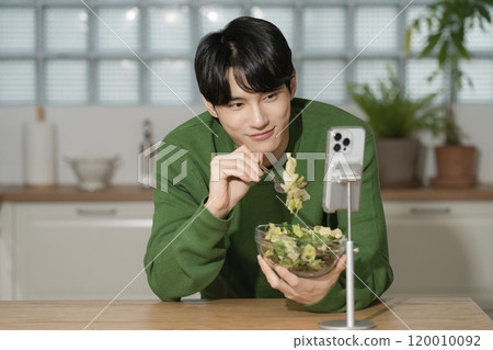 A man in his 20s managing his diet by eating salad 120010092