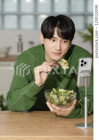 A man in his 20s managing his diet by eating salad 120010096
