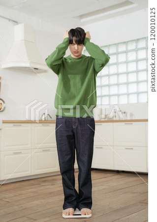 A man in his 20s measuring his weight on a scale A man in his 20s measuring his weight on a scale 120010125