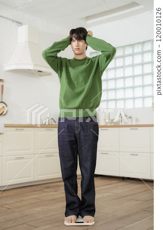 A man in his 20s measuring his weight on a scale A man in his 20s measuring his weight on a scale 120010126