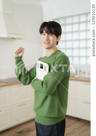 A man in his 20s holding a scale and making a resolution A man in his 20s holding a scale and making a resolution 120010138