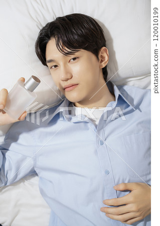 A man in his 20s posing while lying on a bed A man in his 20s posing while lying on a bed 120010199