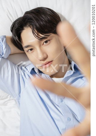 A man in his 20s posing while lying on a bed 120010201