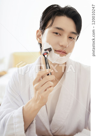 A man in his 20s shaving in front of a mirror A man in his 20s shaving in front of a mirror 120010247