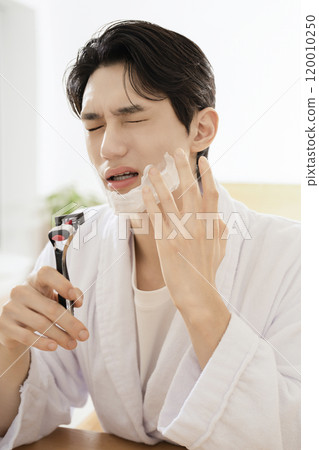 A man in his 20s shaving in front of a mirror A man in his 20s shaving in front of a mirror 120010250