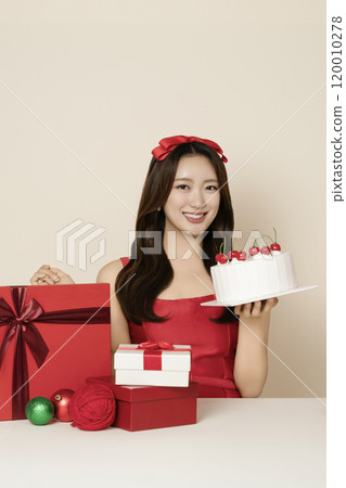 A woman in her 20s wearing a red dress posing with a Christmas cake A woman in her 20s wearing a red dress posing with a Christmas cake 120010278