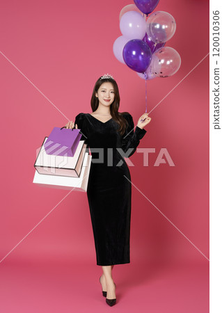 A woman in her 20s wearing a crown and posing with shopping bags and balloons 120010306