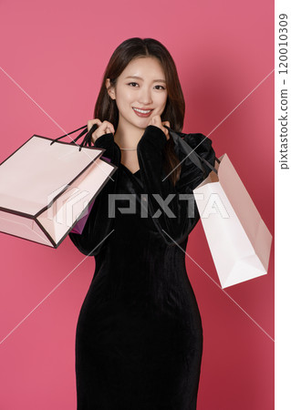 A happy woman in her 20s holding a lot of shopping bags in both hands 120010309