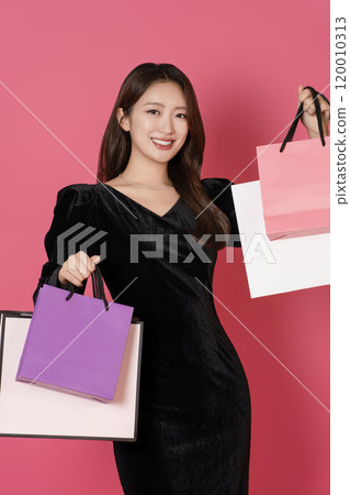 A happy woman in her 20s holding a lot of shopping bags in both hands 120010313
