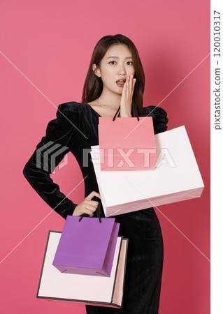 A happy woman in her 20s holding a lot of shopping bags in both hands A happy woman in her 20s holding a lot of shopping bags in both hands 120010317